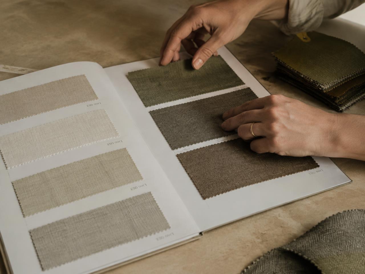 Hands arranging linen swatches inside an open sample book